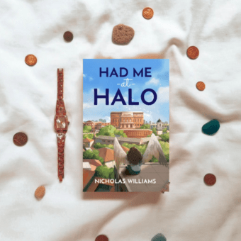 The cover of Had me at Halo surrounded by colourful pebbles and a watch