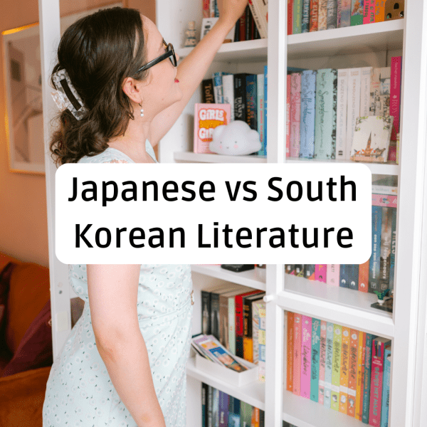 A woman with brown hair in a floral dress reaches for a book on a crowded white bookshelf. Large black text in a rounded white box centered over the image reads, "Japanese vs South Korean Literature."